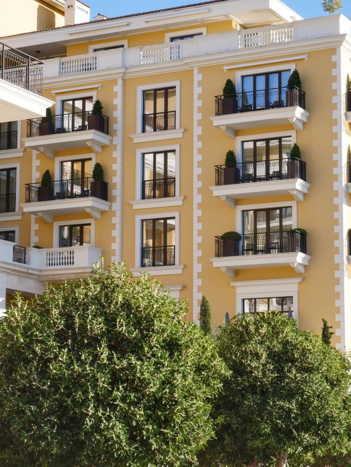 Sunlit view of a charming European-style residential building with balconies and ornamental plants.