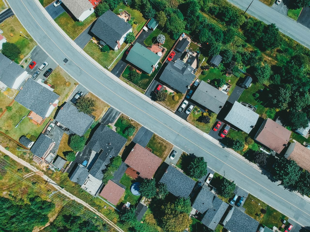 Aerial drone shot capturing suburban neighborhood houses and streets with greenery.